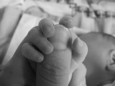 Kleiner Babyfuß in einer Hand, Schwarz-Weiß-Aufnahme