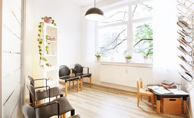 Wartezimmer mit großen Fenstern, Stühlen und Kinderecke